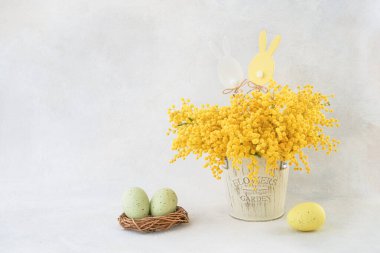 Paskalya süsü ve Mimosa çiçek buketi, arka planda bir vazoda. Metin için alanı kopyala