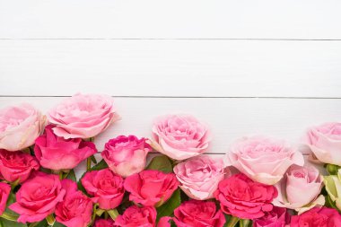 Tebrik kartı. Beyaz ahşap arka planda pembe güllerin sınırı. Anneler günü, sevgililer günü, doğum günü kutlaması konsepti. Tebrik kartı. Boşluğu kopyala, üst görünüm