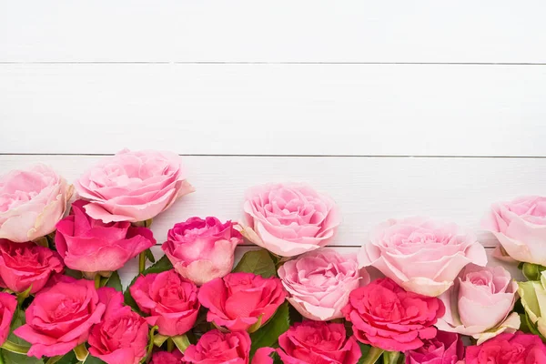 Tebrik kartı. Beyaz ahşap arka planda pembe güllerin sınırı. Anneler günü, sevgililer günü, doğum günü kutlaması konsepti. Tebrik kartı. Boşluğu kopyala, üst görünüm