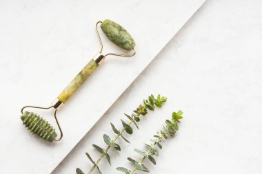 Doğal yeşim taşı ve okaliptüs dallarından gelen yeşil yüz silindiri beyaz arka planda. SPA konsepti