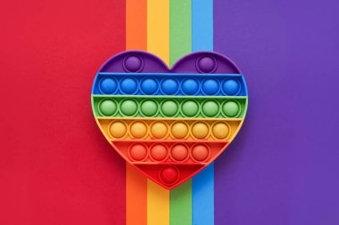 Renkli moda pop, oyuncağı gökkuşağı arka planında kıpır kıpır yapıyor. Oyuncak anti-stres, basit gamze. LGBT konsepti. Üst görünüm