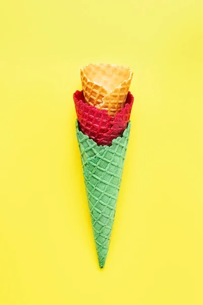 Divers cônes de crème glacée vides sur un fond jaune vif. Concept d'été, vue de dessus — Photo
