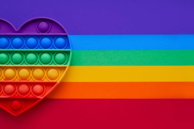 Renkli trend. Gökkuşağı arka planındaki çocuklar için kalp şeklindeki oyuncaklar. Düz yatıyordu