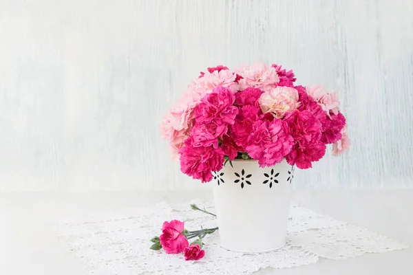 Rosa Nelkenblüten Strauß in weißer Vase auf blauem Hintergrund. — Stockfoto