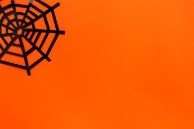 Cadılar bayramı konsepti. Parlak turuncu arka planda dekoratif örümcek ağı. Düz konum, metin için boşluk kopyala