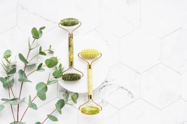 Yeşil yeşim yüzlü silindirler ve beyaz mermer arka planda okaliptüs dalları. SPA konsepti. Üst görünüm, alanı kopyala