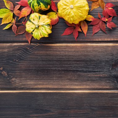 Balkabaklarıyla sonbahar arkaplanı, koyu ahşap bir masanın üzerine düşen renkli yapraklar. Mutlu Şükran Günleri.