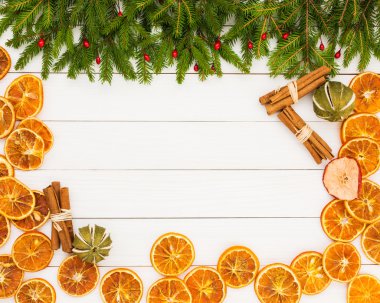 Christmas background. Christmas fir tree, dried oranges, cinnamon on white wooden background with copy space.