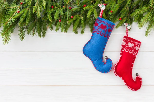 Weihnachtlicher Hintergrund. Tannenbaum mit Deko, rote und blaue Weihnachtssocken auf weißem Holzgrund, Kopierraum — Stockfoto