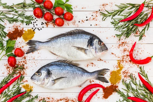 Dorado ryby, rozmarýn, cherry rajčata, chilly papričkou na bílý dřevěný stůl. Pohled shora — Stock fotografie