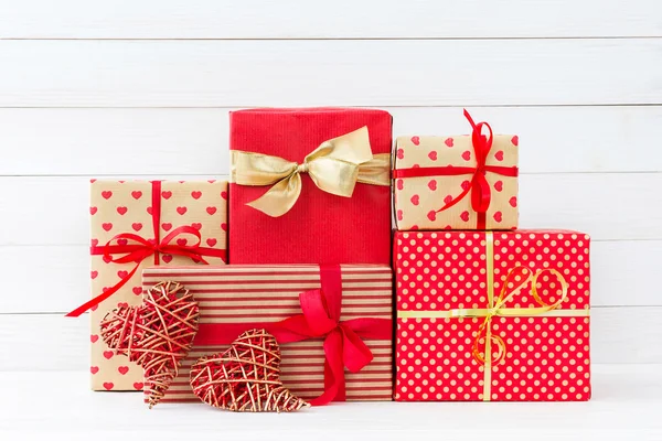 Envuelto cajas de regalos y dos corazones rojos sobre fondo de madera blanca —  Fotos de Stock