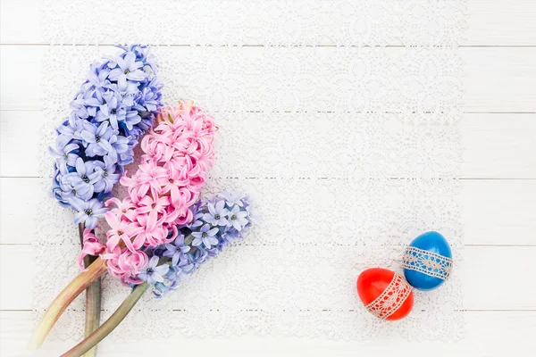Two Easter eggs and hyacinths on white tablecloth. Top view — Stock Photo, Image
