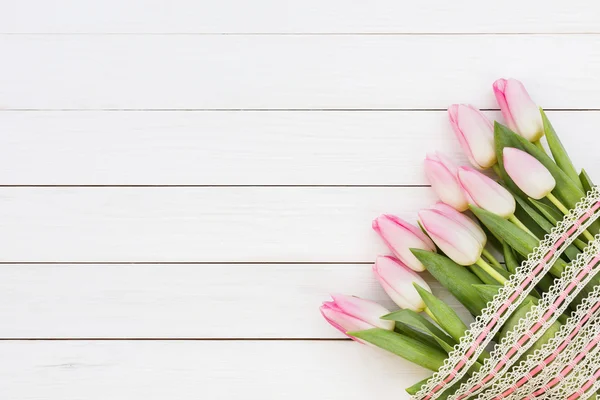 Strauß rosa Tulpen mit Band auf weißem Holzhintergrund dekoriert. — Stockfoto