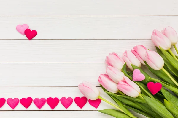 Buquê de tulipas rosa na mesa de madeira branca decorada com corações. Dia dos Namorados fundo — Fotografia de Stock