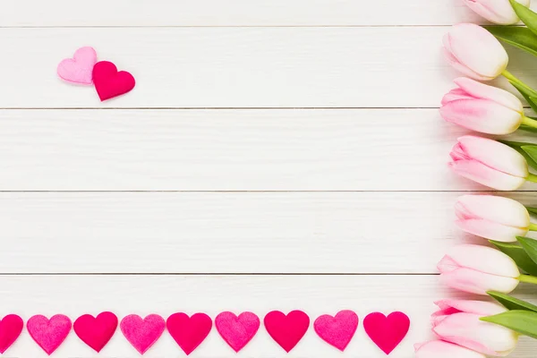 Tulipas cor-de-rosa e coração sobre fundo de madeira branco, fundo de férias — Fotografia de Stock