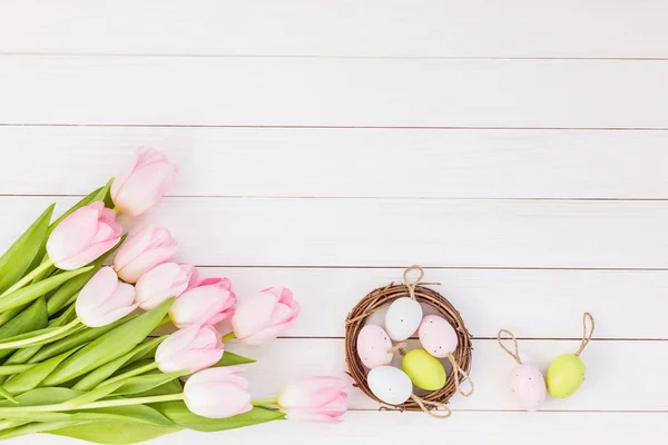 Tulipán és a kis fészek, a fehér asztal dekoratív húsvéti tojás. Szemközti nézet — Stock Fotó