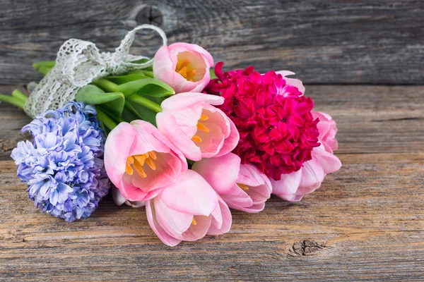 Bouquet of spring flowers decorated with ribbon on old wooden table. — Stock Photo, Image