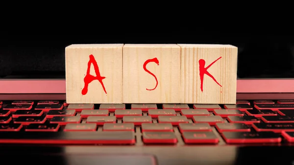 Text ask on wooden cubes that lie on the highlighted laptop keyboard in red — Stock Photo, Image