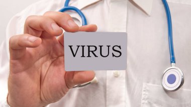 Virüs kelimesi bir doktorun elindeki karta yazıldı. Koronavirüs karantinası konsepti.