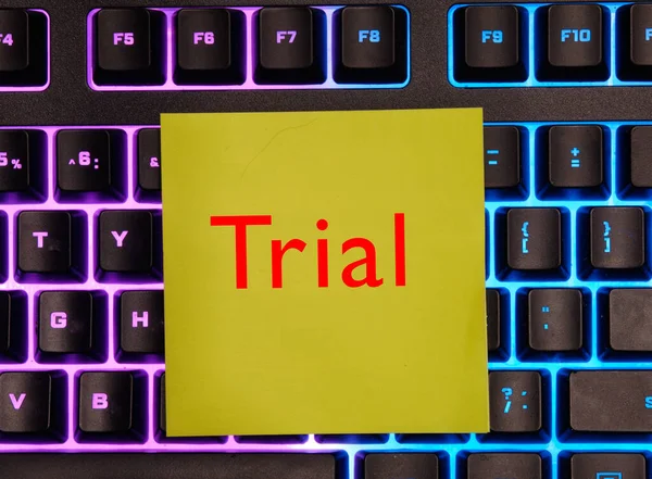 Ord rättegång på gult papper på en bakgrundsbelyst tangentbord bakgrund. — Stockfoto