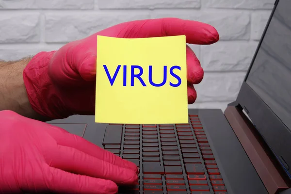 Lidská ruka v červené lékařské rukavici označující slovo virus napsaný písmeny na žlutém papíru — Stock fotografie