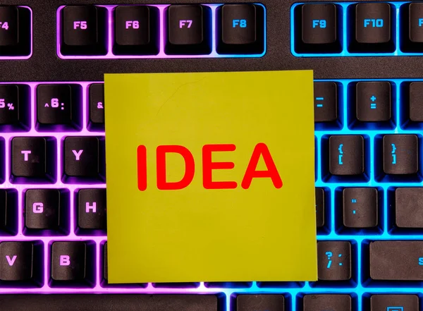 Woord idee geschreven op geel papier. Het papier staat op het toetsenbord. creatief idee — Stockfoto