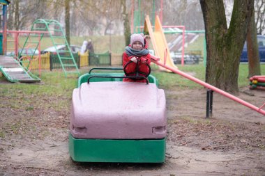 Küçük bir kız eski, modası geçmiş bir bahçede araba sürüyormuş gibi yapıyor..