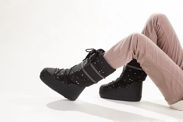 Kvinnans ben i beige byxor och moon boots. — Stockfoto