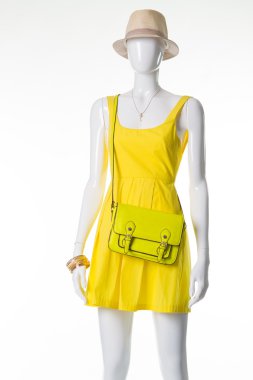 Manken bir sarı elbise, hasır şapka ve ışık yeşil çanta. 