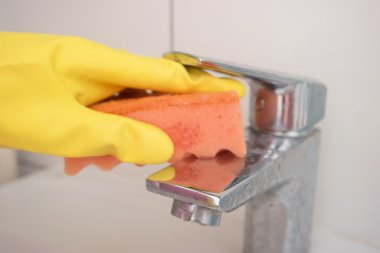 Ev hanımı sarı bir eldiven el musluk yıkar. C