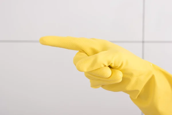 Hand in yellow rubber glove shows an index finger.