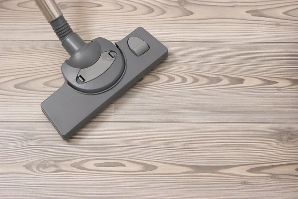 Brush of the vacuum cleaner on a wooden floor.