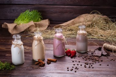 Various milkshakes on the wooden background.