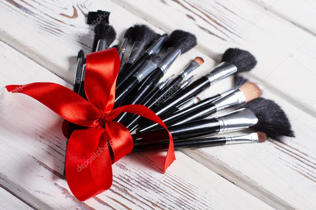 Makeup brushes tied of a red ribbon.