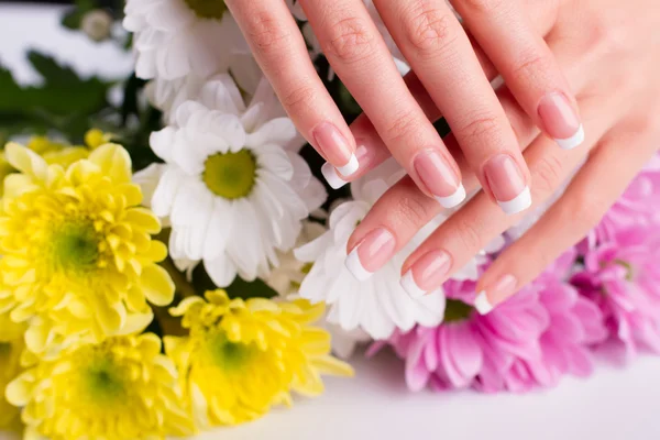 Vrouwen handen op de achtergrond van bloemen. — Stockfoto