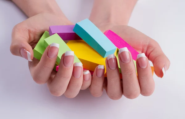 Mãos femininas bem tratadas com objetos coloridos . — Fotografia de Stock