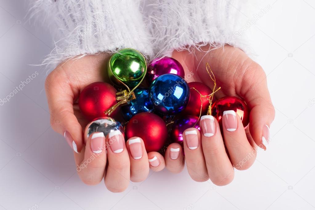 Many colorful Christmas balls in female hands. 