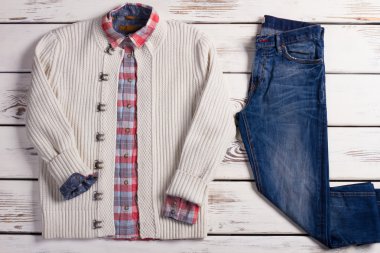 Damalı tişört ve kot pantolon ile beyaz örgü kazak.