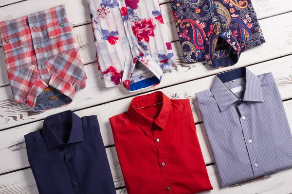 Many bright modern men's shirts with different colors and prints