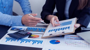 Toplantı yöneticileri pazarlama, ticaret ve yatırım projelerinde ortakların ortaklıklarını analiz eder ve borsayı sunan ve yöneten grafiklere işaret ederler..