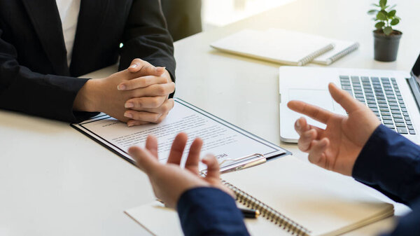 Интервьюеры, которые близки к кандидатам на работу в конференц-зале, офисе на столе, бумагах и ноутбуке на столе.