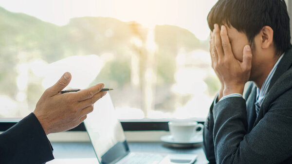 The chief CEO is angry with the office workers who do not work well and Disappointed staff sat at the front of the table with their hands feeling the mood