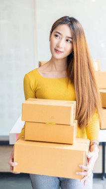 Genç Asyalı internetten bir şeyler satıyor, çalışan bir karton kutuda küçük bir iş kuruyor müşterilere, çevrimiçi satışlara ya da e-ticaret sitelerine gönderi kutuları sağlıyor..