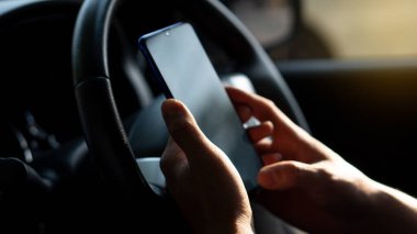 Simulated picture of the driver's hand using a smart phone, black screen inside the car, locating through a near-distance GPS navigation application, parked on the side of the road.