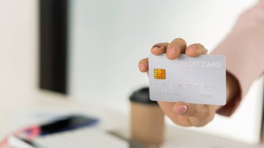 A credit card in the hand of a business woman from a distance