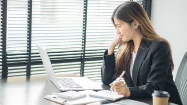 Lovely Asian accountants are happy to work on computers and calculators on the office table.