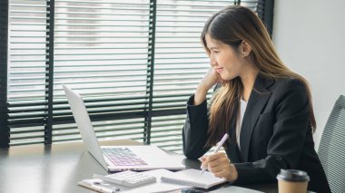Lovely Asian accountants are happy to work on computers and calculators on the office table.