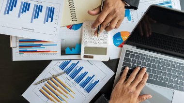 İki işadamı, finans şirketlerinin grafikleri ve analizleri ve hesap makinesi ofislerinin masada kağıtları, laptopları ve kahve fincanları ile kullanımı hakkında konuştular..