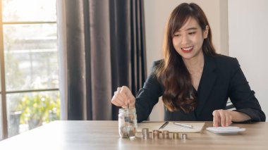 İleride para biriktirmek için pembe kavanozda bozuk para tutan genç bir kadının eli..