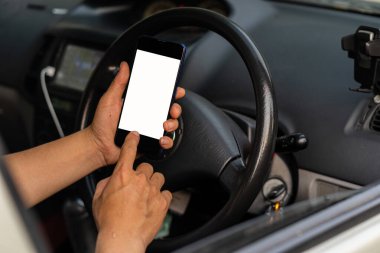 Direksiyonun arka planına karşı bir cep telefonu. Resim Taşımacılığı ve Araç GPS kavramları koymak için beyaz ekranlı bir telefon.